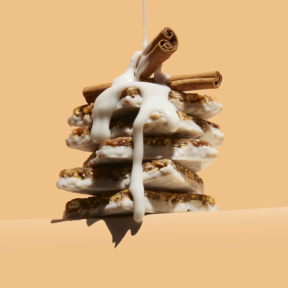 Stacked Arbonne protein bars with icing poured over cinnamon sticks